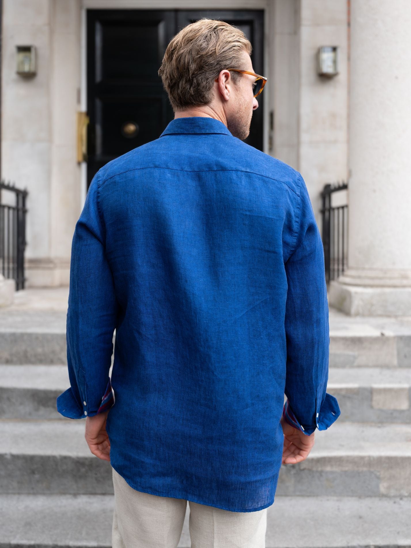 Man wearing a blue jacket standing on steps outside a building